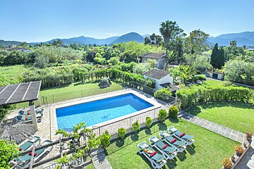 A large swimming pool is surrounded by a lush green lawn
