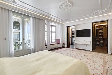 A bedroom with a large bed and a walk in closet