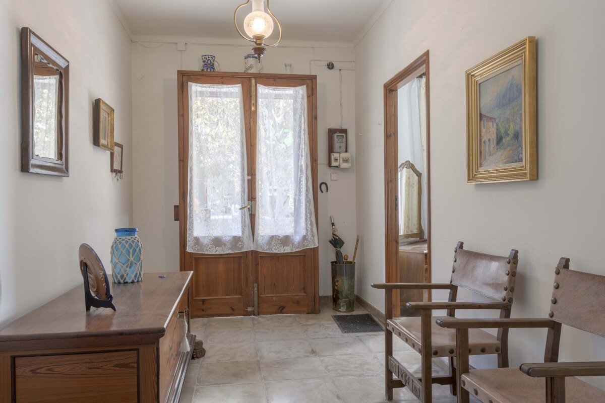 A hallway with a telephone on the wall and a lamp hanging from the ceiling