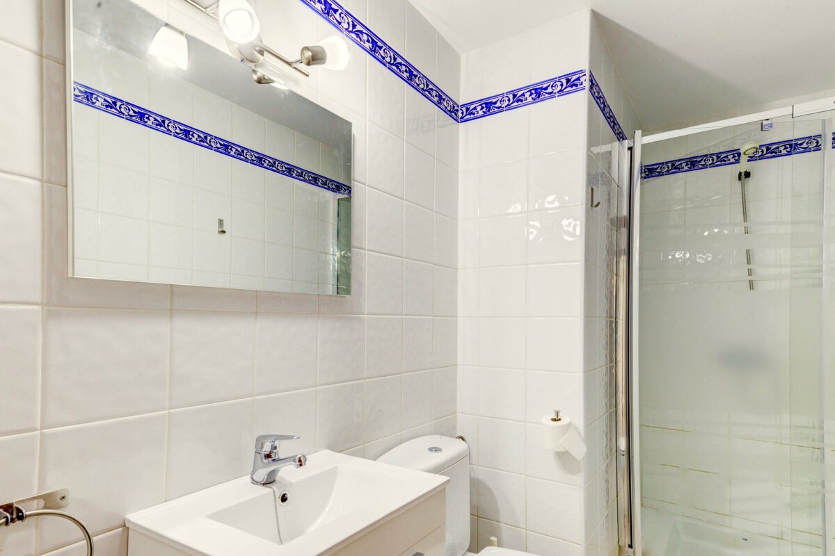 A bathroom with white tiles and a blue border