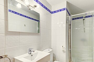 A bathroom with white tiles and a blue border