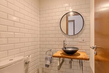 A bathroom with white tiles and a black sink