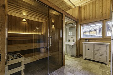 A bathroom with a glass door leading to a sauna