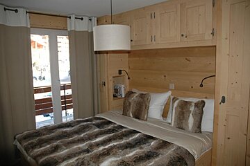 A bed with a fur blanket and pillows in a bedroom