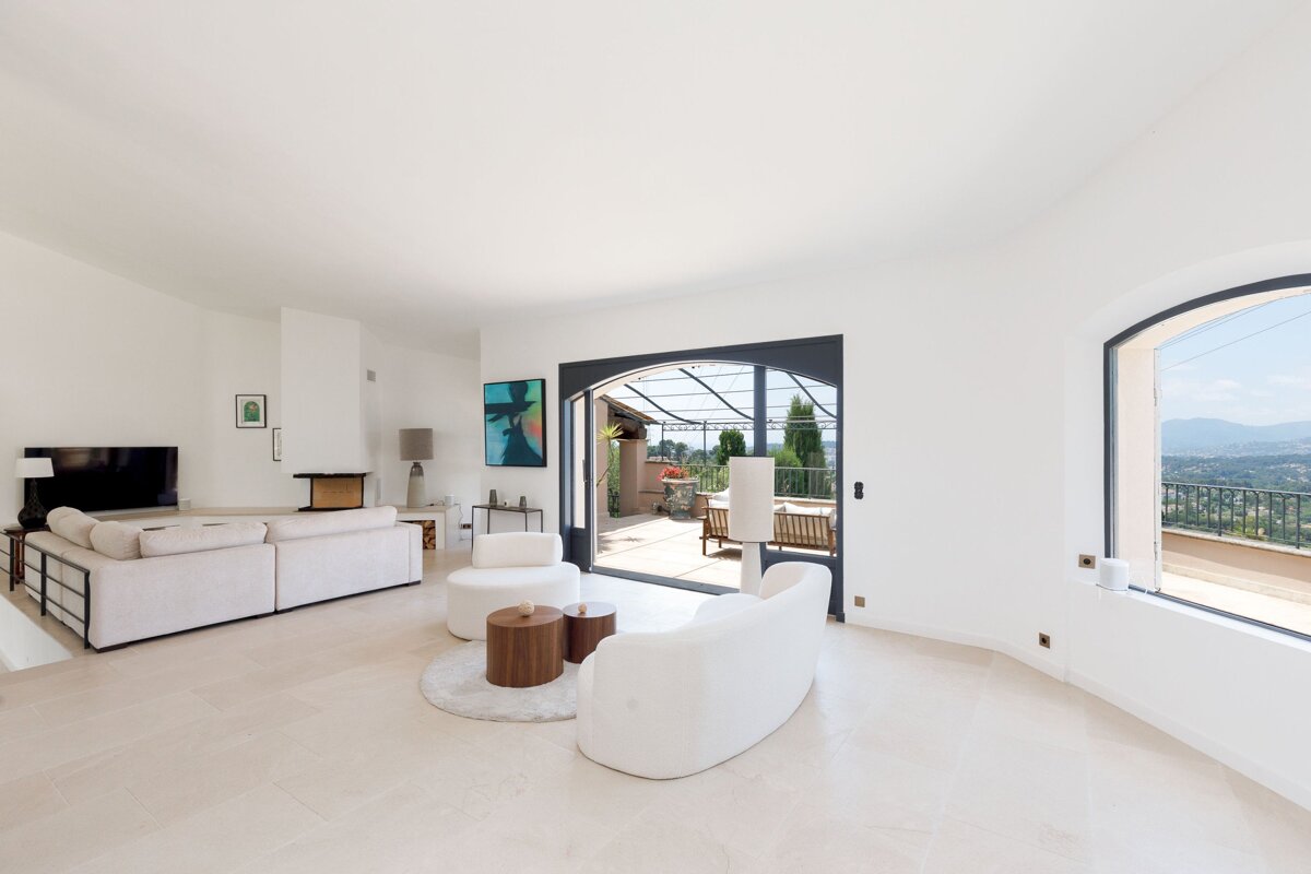 A living room with white furniture and a sliding glass door