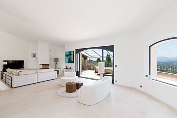 A living room with white furniture and a sliding glass door