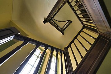 Looking up at a wooden staircase with a yellow wall