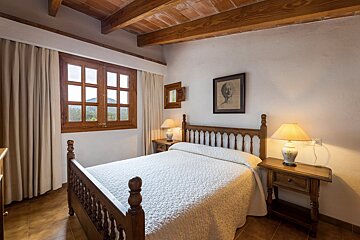 A bedroom with a large bed and two lamps