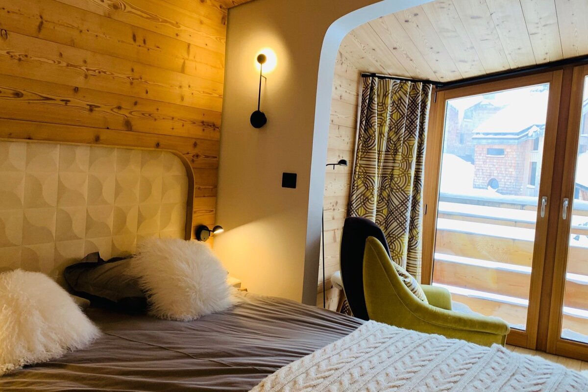 A bedroom with a bed a chair and a window