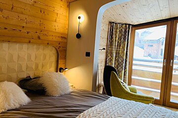 A bedroom with a bed a chair and a window