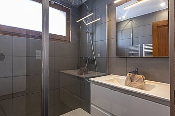 A bathroom with a walk in shower and a sink