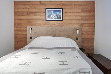 A bed with a blanket that has the letter h on it