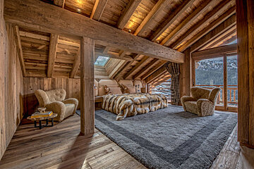 A bedroom with a large bed and two chairs