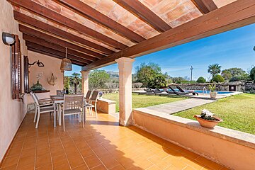 A patio with a table and chairs overlooking a pool