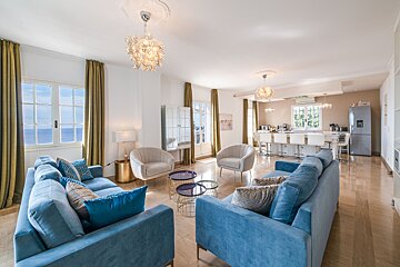 A living room with a blue couch and white chairs