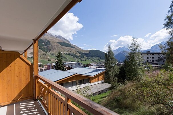 A balcony overlooking a valley with mountains in the background