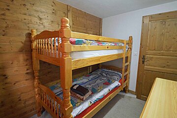 A bunk bed in a room with a wooden wall