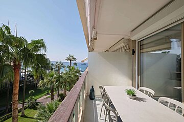 A balcony with a table and chairs overlooking the ocean