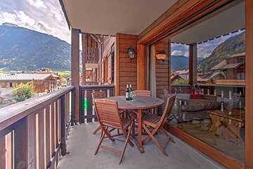 A balcony with a table and chairs and two bottles of wine