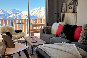 A living room with a couch and a chair and a view of the mountains