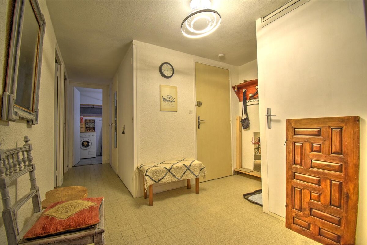 A hallway with a wooden door and a clock on the wall