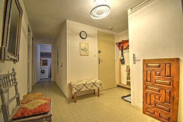 A hallway with a wooden door and a clock on the wall