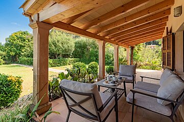A porch with a couch and chairs under a wooden roof