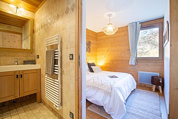 A bedroom with a white bed and a white towel rack