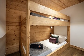 A wooden bunk bed with a blanket that says nordic night on it