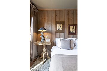 A bedroom with a bed and a table with a lamp on it