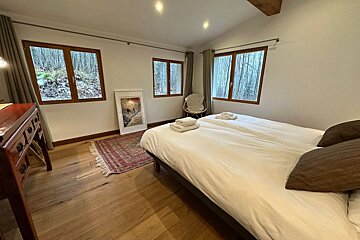 A bedroom with a large bed and a chair