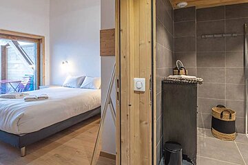 A bedroom with a large bed and a walk in shower
