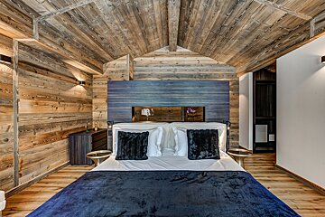 A bedroom with wooden walls and a blue headboard