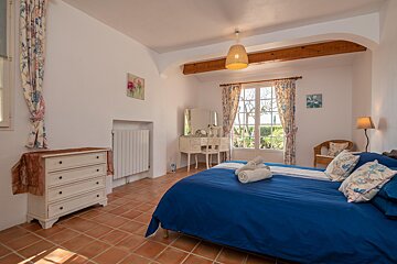 A bedroom with a blue bed and a white dresser