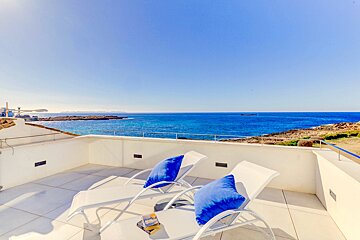 Two lounge chairs on a balcony overlooking the ocean