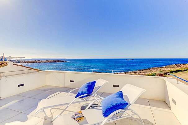 Two lounge chairs on a balcony overlooking the ocean