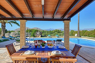 A table with plates and wine glasses on it in front of a pool
