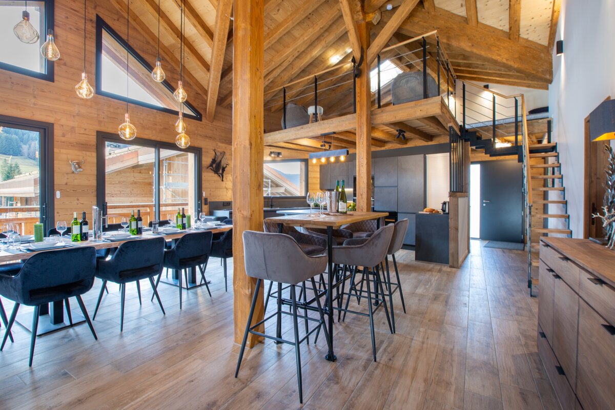 A dining room with a table and chairs and bottles of wine