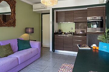 A living room with a purple couch and a kitchen