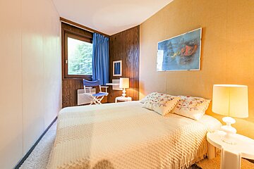 A bedroom with a painting on the wall above the bed