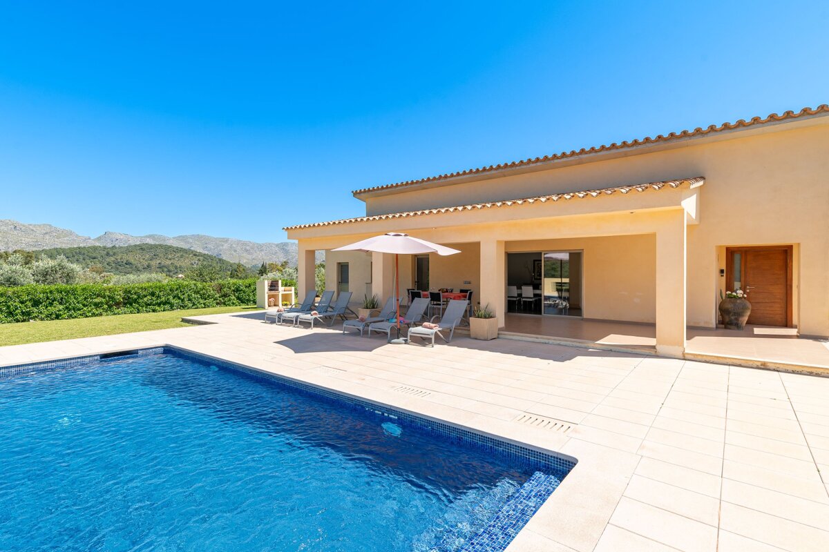 A house with a swimming pool and chairs under an umbrella
