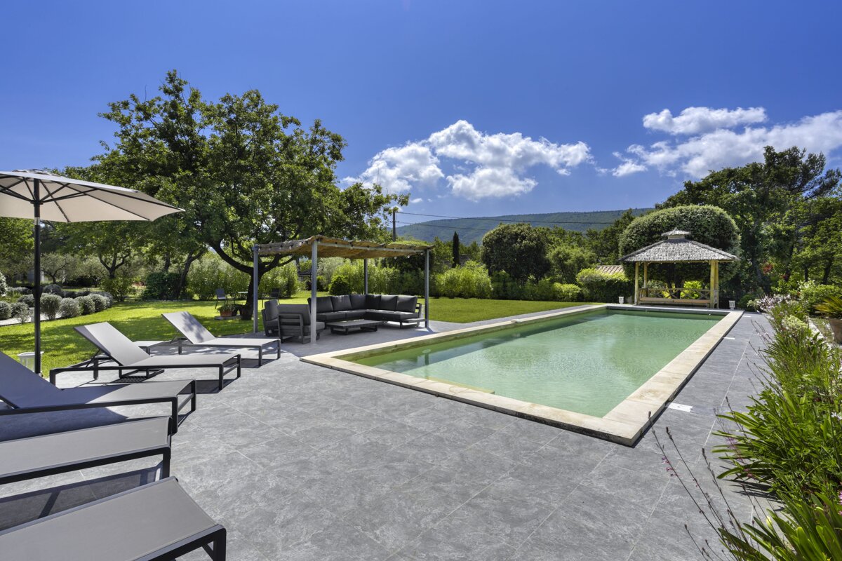 A large swimming pool with a gazebo in the background