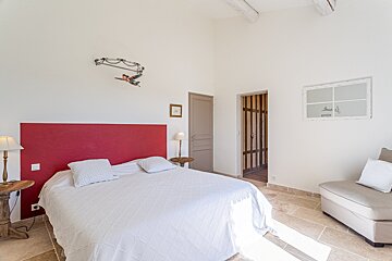 A bedroom with a white bed and a red headboard