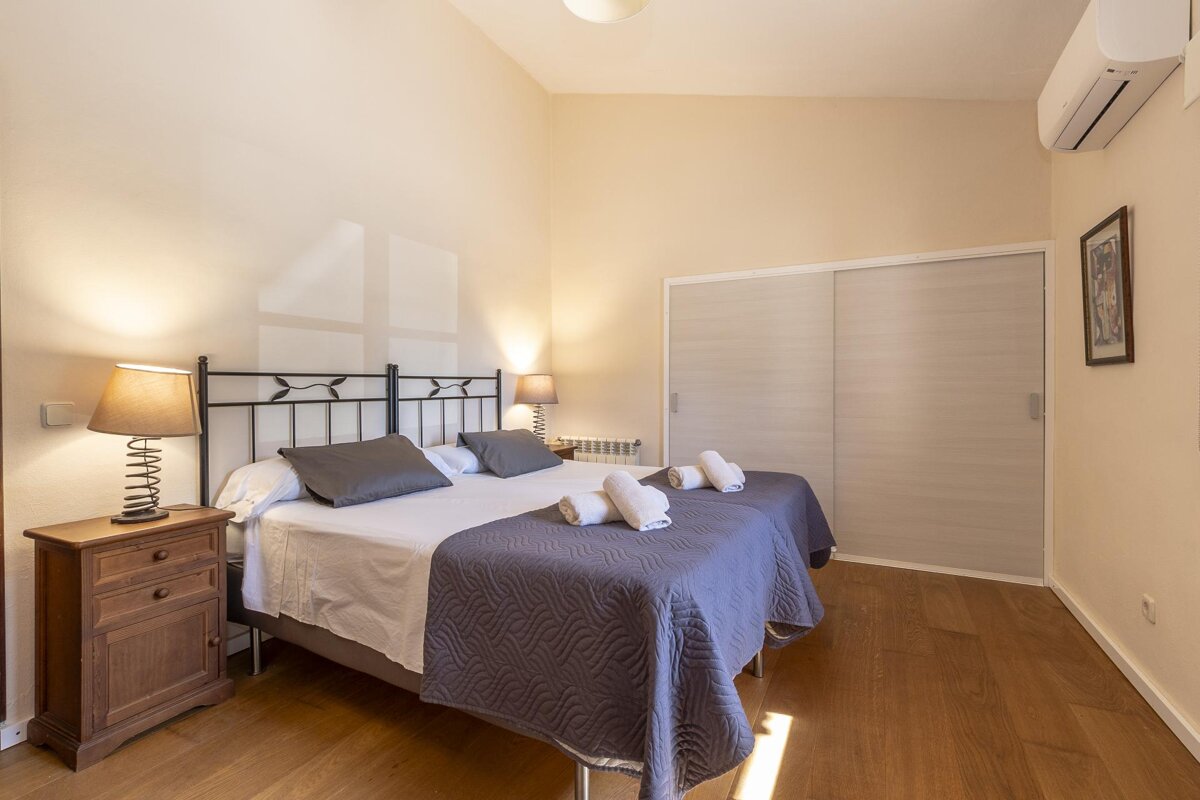 A bedroom with two beds a nightstand and a lamp