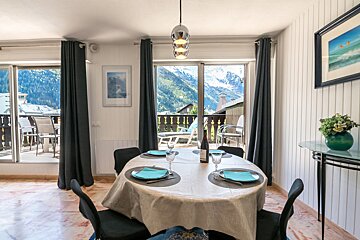 A dining room table with a bottle of wine on it