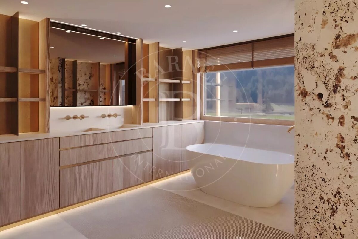 Sleek modern bathroom with light wood vanity, double sinks, freestanding tub, and a large window. Illuminated by accent lighting, featuring a textured wall.
