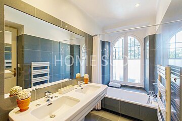 A bathroom with two sinks and a bathtub has the word home on the wall