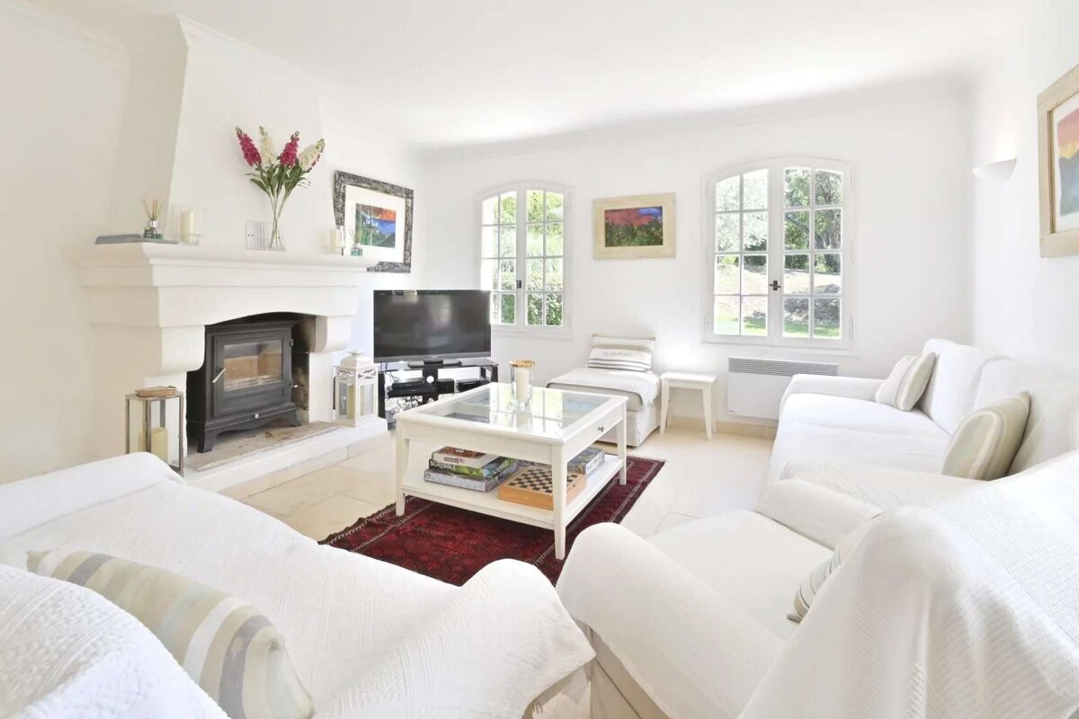 A living room with white furniture and a fireplace
