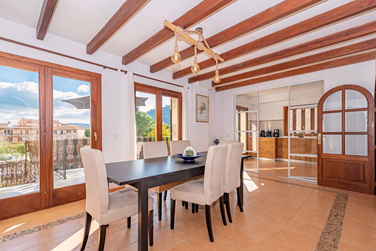 A dining room with a table and chairs under a wooden ceiling