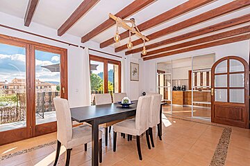 A dining room with a table and chairs under a wooden ceiling